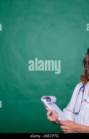 Doctor filling medical report for her patient.Doctor with stethoscope in white coat holding clipboard, writing medical record diagnosis, isolated on Stock Photo
