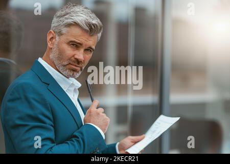 Smiling mature businessman standing outside of office with documents Stock Photo