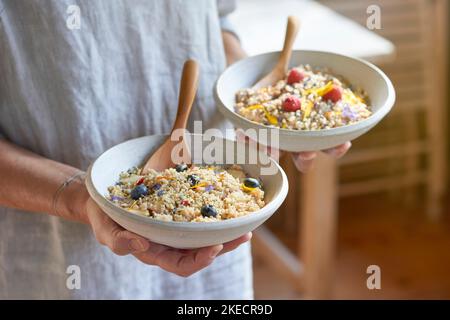 ayurvedic cuisine, woman holding two light clay bowls with semolina porridge and fruits in her hands Stock Photo