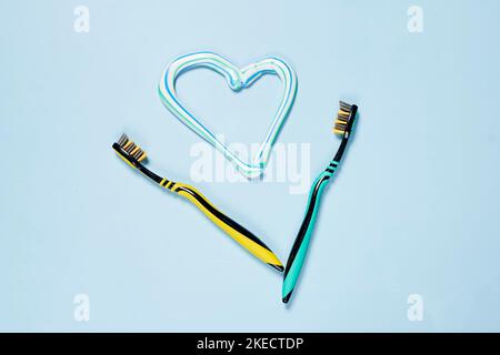 two tooth brushes and a heart shaped brush on a light blue background with copy space in the top right corner Stock Photo