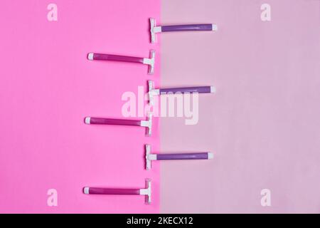 three toothbrushs on a pink and white background with the one in between it to the other two brushes Stock Photo