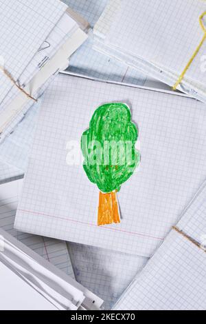 a green tree on top of paper with pencils and crayon pens in the bottom right corner, next to it is Stock Photo