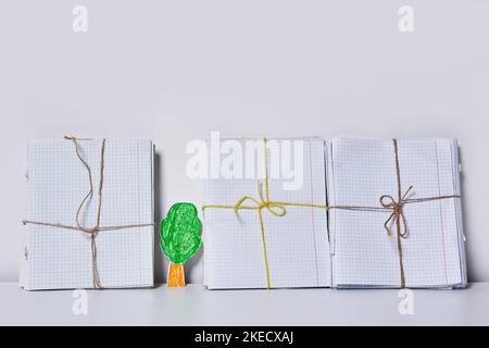 three notebooks wrapped in twine and tied to each other one with a green leaf on the left side Stock Photo