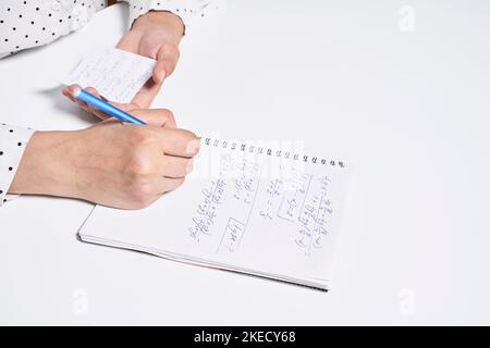someone's hand holding a pen and writing on a piece of paper that has been written in several different languages Stock Photo