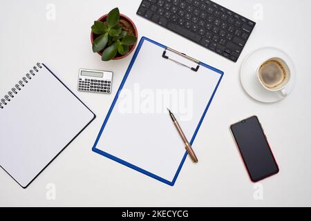 an office desk with a laptop, notepad, pen and coffee on it next to a cup of coffee Stock Photo