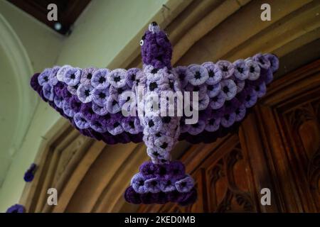 Beaconsfield, Buckinghamshire, UK. 11th November, 2022. A dove covered in purple knitted poppies at the Parish Church in Beaconsfield for Remembrance Day. Credit: Maureen McLean/Alamy Live News Stock Photo