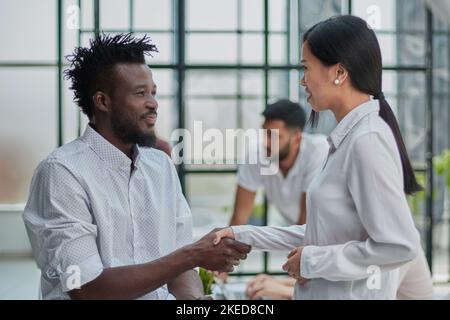 Business Handshake - business people shaking hands. Handshake between business man and woman indoors. Stock Photo
