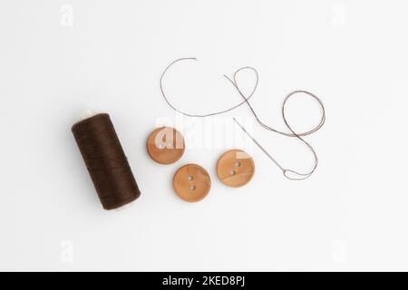 needle with thread and wooden buttons isolated on white background, concept of sewing and repairing clothes Stock Photo