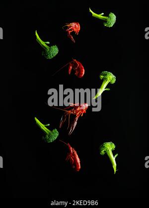 On a black background, boiled crayfish and broccoli in a frozen flight. Stylish culinary composition. Vitamins, proteins, healthy food. There are no p Stock Photo