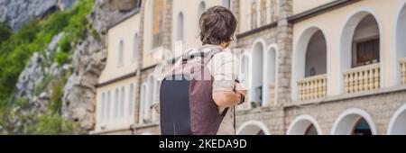 BANNER, LONG FORMAT Man tourist in Monastery of Ostrog, Serbian Orthodox Church situated against a vertical background, high up in the large rock of Stock Photo