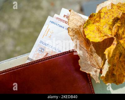 Several Croatian Croatia Kuna Kune Kunas banknotes peering from brief wallet outdoor on table isolated outdoors natural background Stock Photo