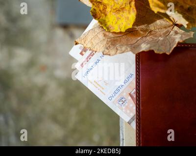 Several Croatian Croatia Kuna Kune Kunas banknotes peering from brief wallet outdoor on table isolated outdoors natural background Stock Photo