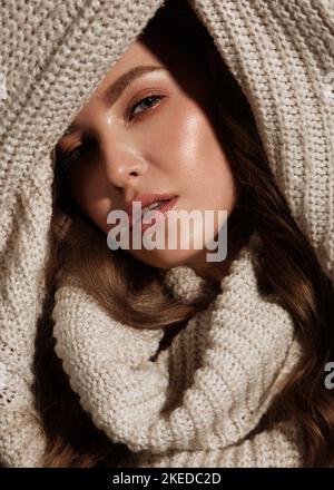 Beautiful young girl with gentle make-up in warm sweater and long straight hair. Beauty face. Stock Photo