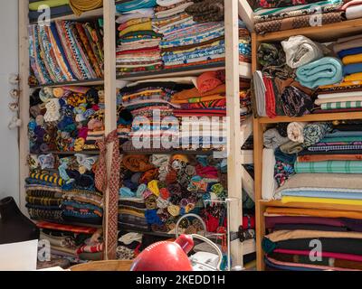 Tailor's workplace. Folded and rolled fabrics on wooden shelves. Stock Photo