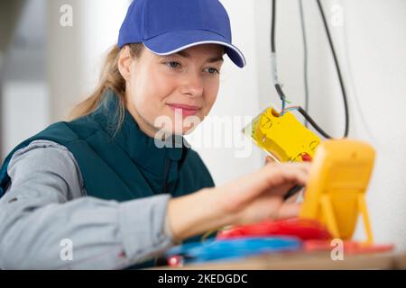 female electrician using multimeter on circuit breaker cabinet Stock Photo