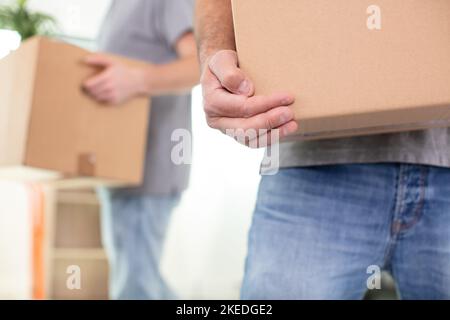 close-up of two mover hand in uniform carrying cardboard box Stock Photo
