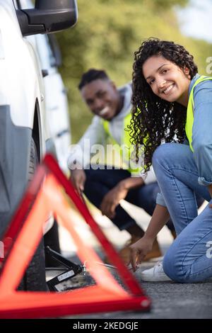 couple after a car breakdown changing wheel Stock Photo