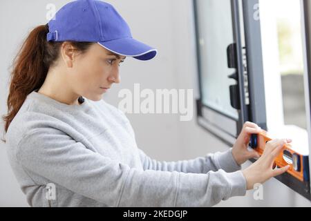 female builder using a spirit level on a window Stock Photo