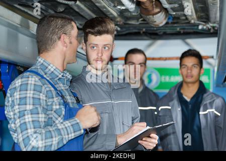 mechanic teaching trainees in garage workshop Stock Photo