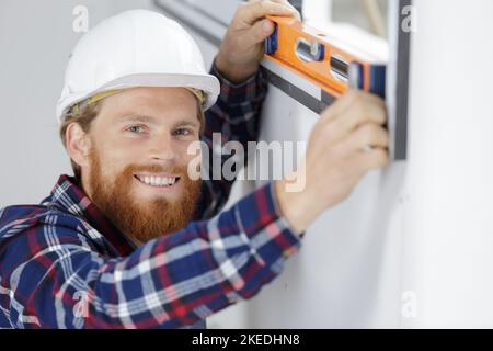 male worker taking measurements of window in flat Stock Photo