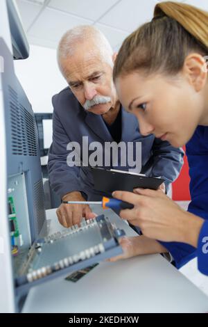 apprentice technician with screwdriver working on electrical appliance Stock Photo