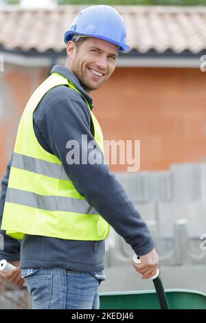 happy construction worker pushing a wheelbarrow Stock Photo
