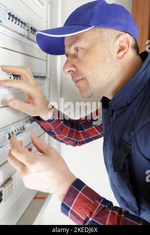side-view of male technician examining fusebox Stock Photo