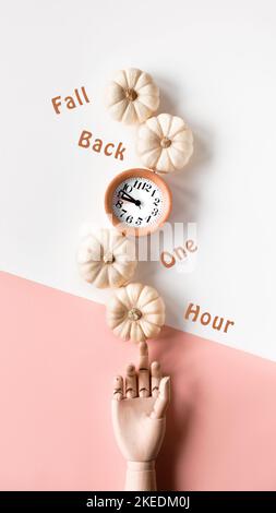 Time change in Autumn. Text Fall Back 1 hour on circle stone board. Wooden alarm clock, with dry Fall leaves on recycled cardboard. Top view, monochro Stock Photo