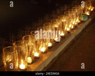 Tea lights in pint glasses lined up against the glass sides of Shoreham Footbridge, to commemorate the victims of the 2015 Shoreham Airshow crash. Stock Photo