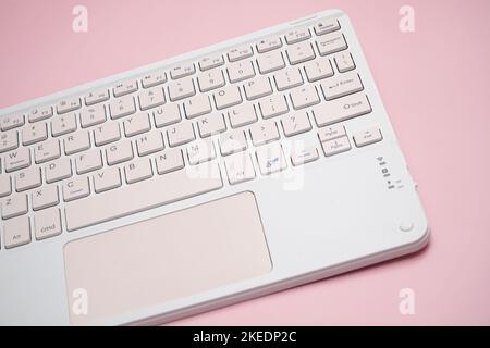 working with wireless external portable keyboard isolated pink background Stock Photo