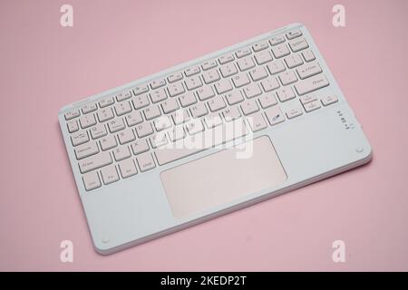 working with wireless external portable keyboard isolated pink background Stock Photo