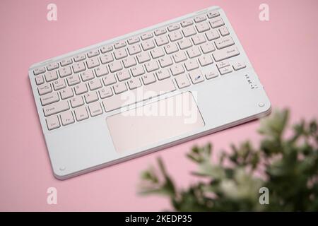 working with wireless external portable keyboard isolated pink background Stock Photo