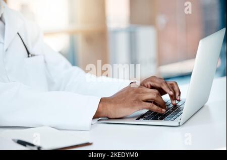 Doctor, hands and typing on laptop in office, working on research or online consultation. Healthcare, computer and black male physician writing Stock Photo