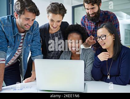 Using technology to maximise productivity. colleagues working together on a laptop in a modern office. Stock Photo
