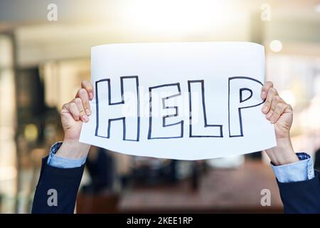 Lend a helping hand. a businessman holding up a sign asking for help. Stock Photo