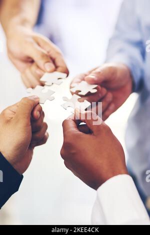 Putting the pieces together. Closeup shot of a group of unidentifiable businesspeople holding puzzle pieces together. Stock Photo