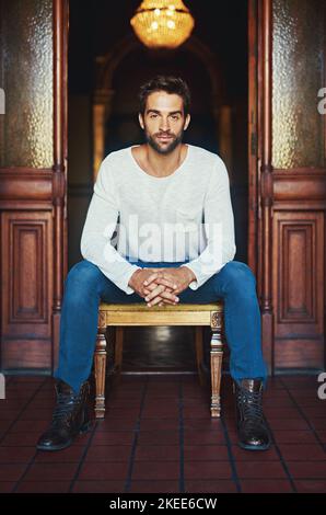 Casual mode, on. Portrait of a handsome man dressed in casual wear posing on a chair. Stock Photo