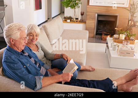 Couples who read together stay together. a relaxed senior couple reading a book together on the sofa at home. Stock Photo