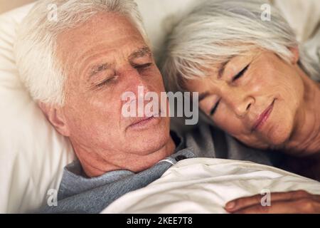 Next to him is the safest place for me. a senior couple sleeping in bed. Stock Photo