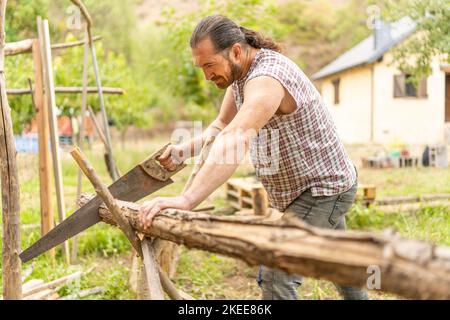 Man cutting a log using a handsaw at home Stock Photo
