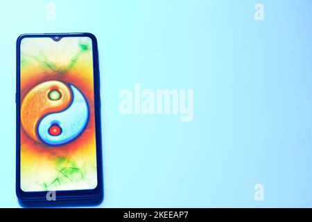 Mobile phone with a yin yang sign in a gentle blue background Stock Photo