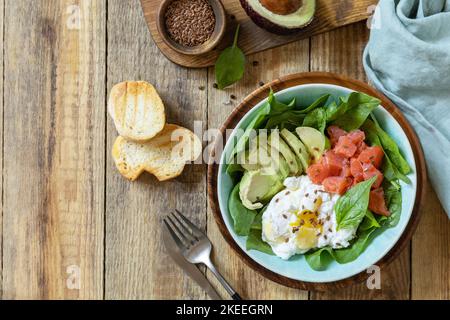 Ketogenic, keto or paleo diet. Delicious breakfast or lunch bowl with salted salmon fish, avocado, boiled egg and spinach on a rustic table. View from Stock Photo