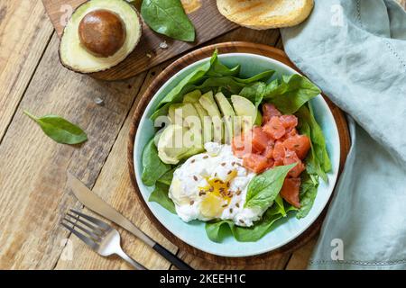 Delicious breakfast or lunch bowl with salted salmon fish, avocado, boiled egg and spinach on a rustic table. Ketogenic, keto or paleo diet. View from Stock Photo