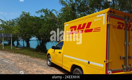 KOH CHANG, TRAT, THAILAND - 11 NOVEMBER 2022: DHL delivery van. Dhl is global market leader in logistics industry. The car is on the beach. Driver is resting in tropical exotic island at sunny day Stock Photo