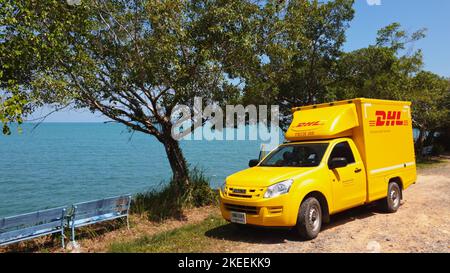 KOH CHANG, TRAT, THAILAND - 11 NOVEMBER 2022: DHL delivery van. Dhl is global market leader in logistics industry. The car is on the beach. Driver is resting in tropical exotic island at sunny day Stock Photo