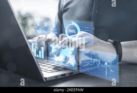 Businessman with laptop and virtual screen with graphs of financial and economic indicators. Digital transformation in global business. ESG- Environme Stock Photo