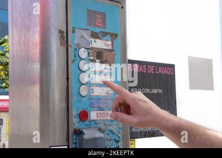 A finger choosing a washing program on a car wash machine Stock Photo
