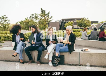 Multiethnic business people doing lunch break outdoor from office building - Focus on arabian girl face Stock Photo