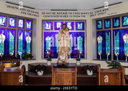 Side altar of St. Joseph and the baby Jesus surrounded by beautiful stained glass windows at St. Ambrose Catholic Church in Woodbury, Wisconsin USA Stock Photo