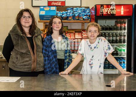 Young girls behind the counter of a concession stand selling food and drinks for an event. Stock Photo